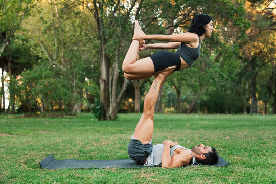 Man balancing girlfriend on legs while doing acroyoga in park
