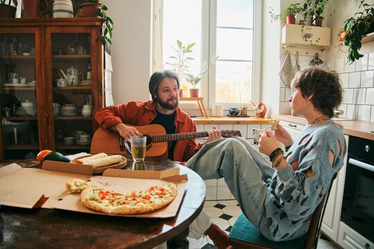 Couple enjoying pizza and music together at home in the living room