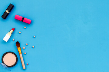 Flatlay of makeup cosmetics on blue background. Blusher, mascara and lipstick, top view