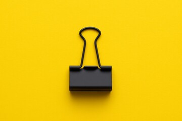 Black binder clip centered on yellow background
