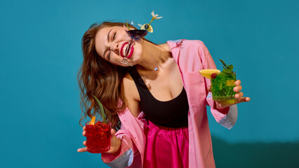 Joyful woman in pink outfit holding colorful cocktails with playful energy and bright mood. Concept...