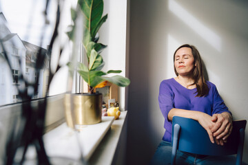 Mature woman enjoying a peaceful moment at home in the sunlight