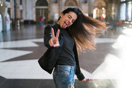 Portrait of exuberant young woman with lollipop in station concourse