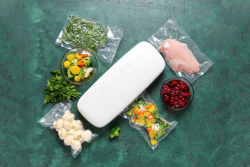Vacuum sealer machine with food in packs on green grunge background
