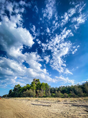 Obraz premium Torre di Cerrano rises majestically from the green vegetation of Pineto's beach, under a breathtaking cloudy sky in Abruzzo, Italy