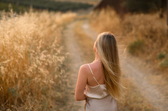 Slavic woman with long white hair standing in golden grass field, natural beauty and ethnic portrait in summer countryside landscape at sunset.