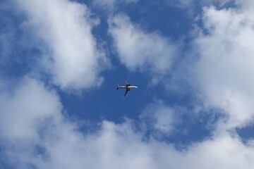 Commercial Airplane Flying Overhead in Blue Sky with Scattered Clouds