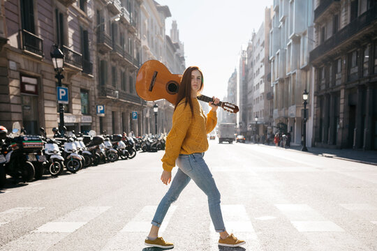 Red-haired woman with a guitar on zebra crossing
