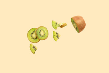 Ripe cut kiwi flying against color background