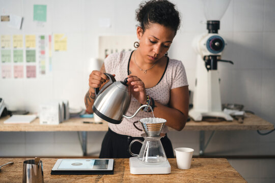 Woman working in a coffee roastery preparing fresh filtered coffee
