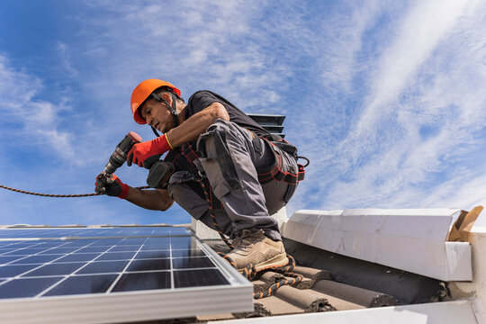 Technician using drill machine and installing solar panels on roof