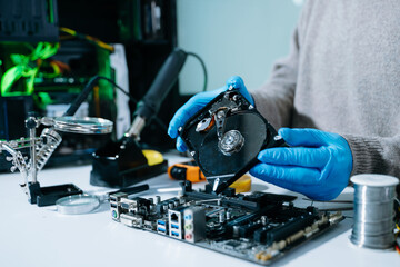 Hard disk drive on the technician's desk and a computer motherboard as a component. the concept of...