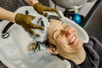 Woman in hair salon getting hair washed with brushes