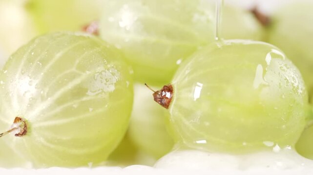 Close-up of fresh gooseberries with water flowing over them, highlighting the texture and juiciness of the fruit. Perfect for food, healthy living, and nature-related content.