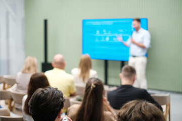 Business leader presenting ideas on screen to an engaged audience in vibrant setting