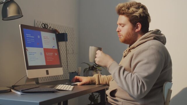 Horizontal medium shot of young Caucasian man with spending time at home making presentation about brand identity on computer