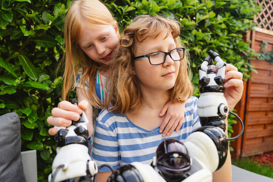 Happy sisters playing with toy robot in garden