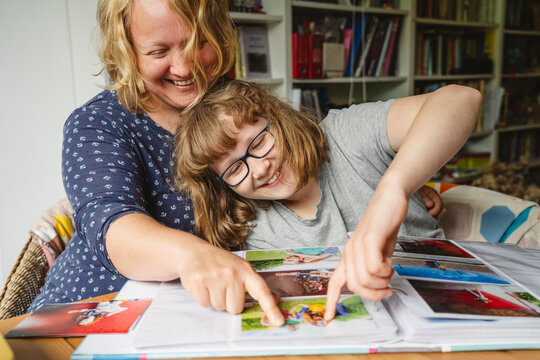 Happy mother and daughter pointing at photographs in album