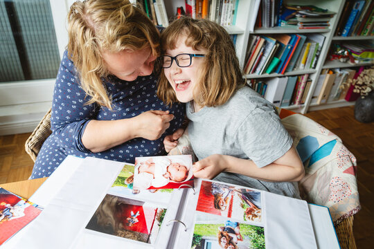 Cheerful mother and daughter laughing at photographs