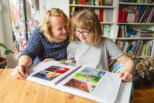 Smiling mother and daughter looking at photo album