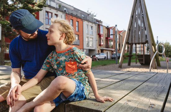 Mature man with arm around son at playground