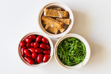 Three white plates with multi coloured herbs and berries, which are picked in a garden. 