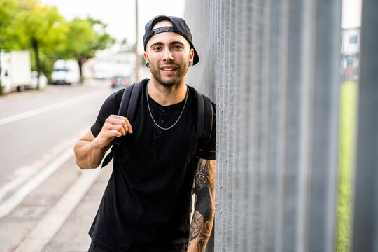 Portrait of a young smiling man with baseball cap in the city