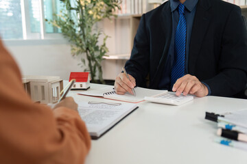 Real Estate Meeting. Client discussing property details with agent using calculator.