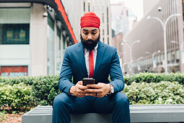 Indian businessman sitting in Manhattan, using smartphone