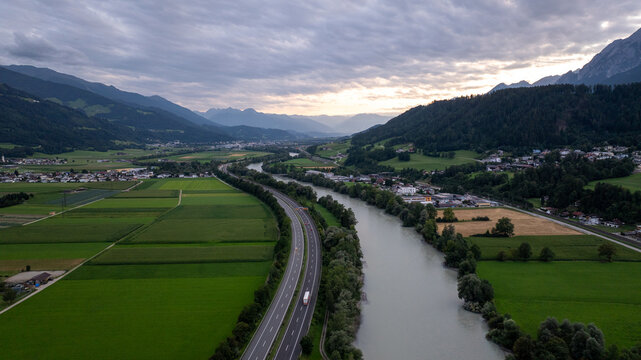 Aerial view of the innerste valley and river inn winding through lush green meadows at sunset, near weer, Tyrol, Austria