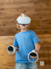 Child wearing VR headset, interacting with digital environment through motion sensing controllers...