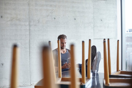 Man using tablet at table with chairs on it