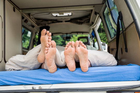 Feet of a couple lying on mattress in van