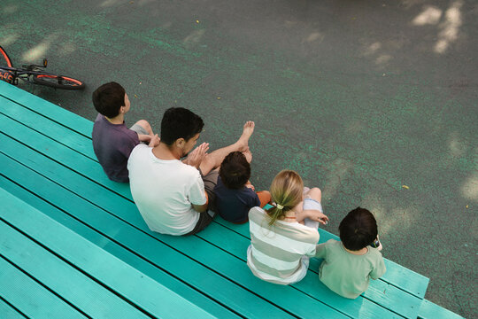 Family spending time together sitting outdoors on turquoise bench