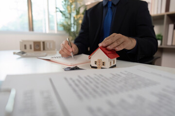 Real Estate Agent Writing Notes with House Model.