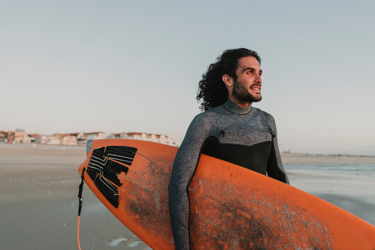 Portrait of surfer on the beach at sunset, Costa Nova, Portugal