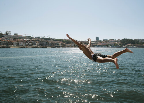 Young man jumping into the water, Porto, Portugal