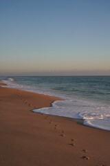 footprints on sandy beach at sunset