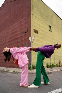 Friends holding hands and bending together in front of building