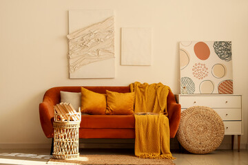 Cosy sofa, chest of drawers and tray with books in interior of living room