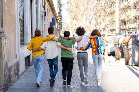 Rear view of group of friends walking arm in arm in the city