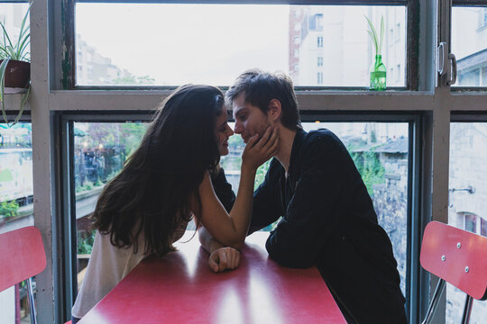 Young couple in love sitting at table at the window