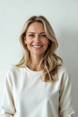 Joyful portrait of a beautiful middle-aged Scandinavian woman with blonde hair, smiling confidently against a plain white studio background.