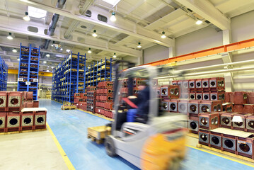 forklift and high shelves with industrial goods in a goods warehouse of a factory