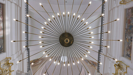 Modern Chandelier Illuminating Church Ceiling with Frescoed Walls