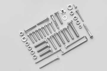 Arrangement of different tap bolts, screws and chrome nuts on grey background