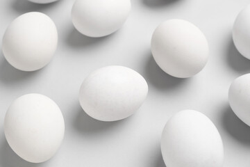 Many raw chicken eggs on grey background
