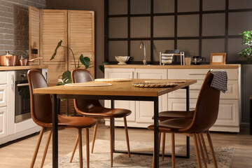 Interior of kitchen with counters, dining table and folding screen in evening