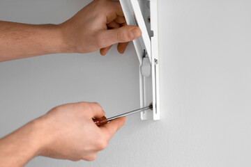 Male carpenter tightening screw in shelf with screwdriver, closeup