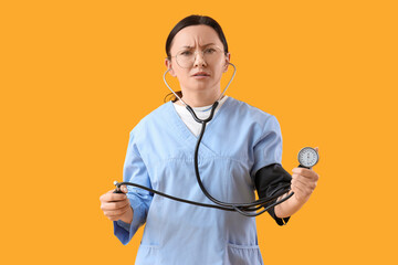 Worried nurse measuring her blood pressure on yellow background